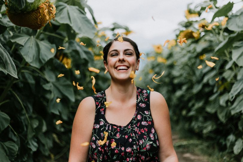 Women smiling with her eyes closed in a field.